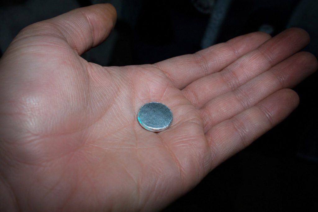 "A small metal knockout disc lying in an open palm held under a sink, the cupboard dark behind the hand" — cheapest first, and on a newly installed machine this disc is the whole answer