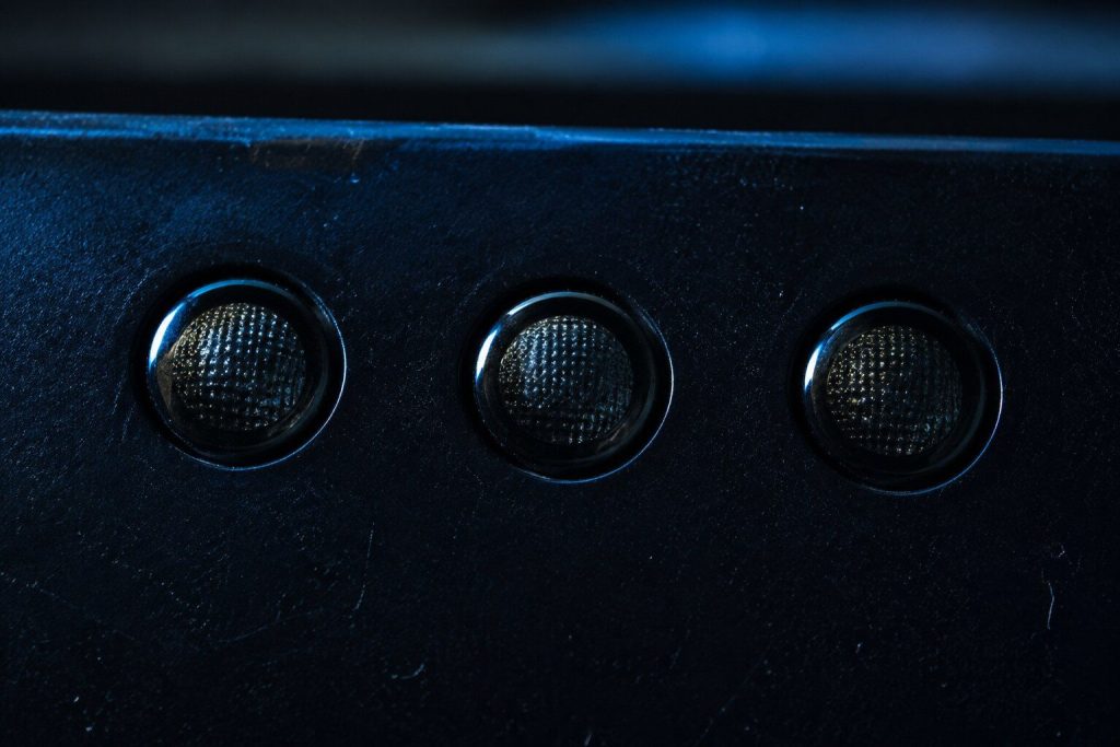A row of three small unlit indicator lamps on a dark panel that is otherwise featureless.