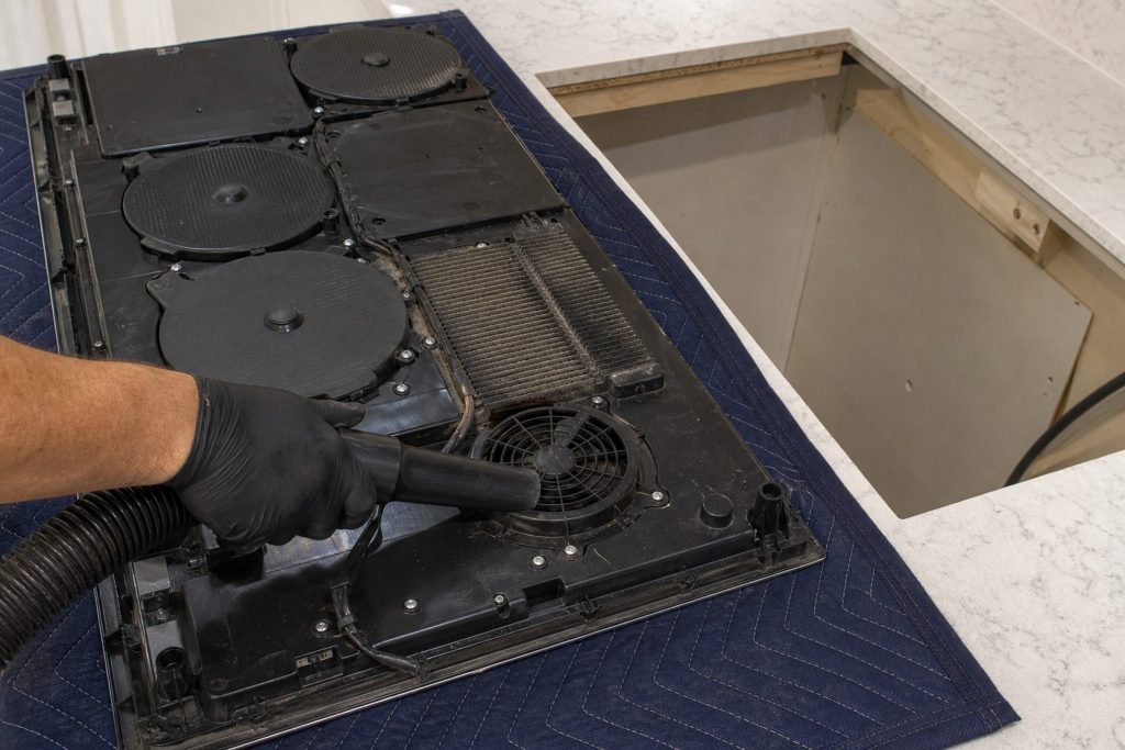 "An induction cooktop with its coils and board exposed" — coils and a board rather than a resistance element, which is the distinction this page opens with. Its own library notes it was preferred over a bright room shot of an intact hob, which is the same choice cobalt would make